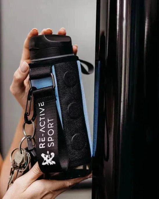 Hand holding an Arctic Blue Magnetic Gym Caddy with a black strap, keys, and "RE-ACTIVE SPORT" tag.