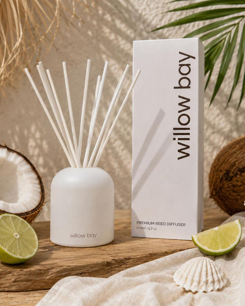 White Willow Bay Coastal Coconut reed diffuser with reeds, packaging, coconuts, limes, and seashells.